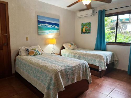 1 dormitorio con 2 camas y ventana en Villa Serenidad en Paquera