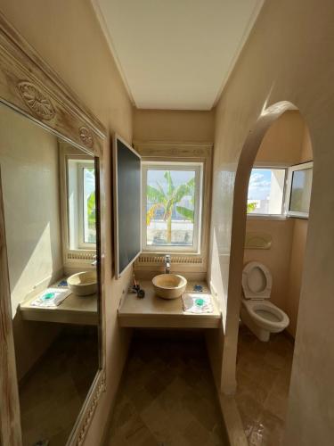 a bathroom with two sinks and a toilet with two mirrors at DAR ELHOUCINE in Hammamet