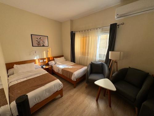 um quarto de hotel com duas camas e uma cadeira em Marron Serviced Studios and Rooms em Cairo