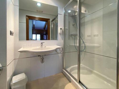 y baño blanco con lavabo y ducha. en Hostal Rey Pedro I, en Santo Domingo de la Calzada