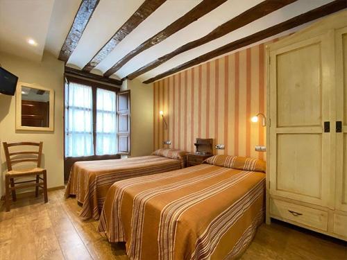 a hotel room with two beds and a window at Hostal Rey Pedro I in Santo Domingo de la Calzada