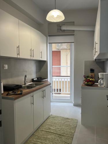 a kitchen with white cabinets and a large window at Acropolis Luxury Apartments Parthenon view in Athens