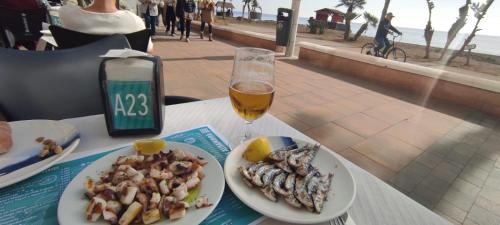 una mesa con dos platos de comida y un vaso de cerveza en Appartement avec vue sur baie de Malaga, en Torre de Benagalbón