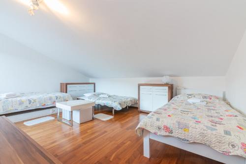 a room with three beds and a wooden floor at Apartment Ruzmarinka with Spacy Terrace in Baška