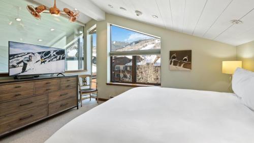a bedroom with a large bed and a flat screen tv at Skijor Chalet in Vail