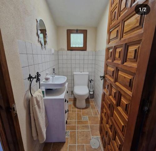 a bathroom with a toilet and a sink and a door at La Cabaña de Conquezuela in Conquezuela