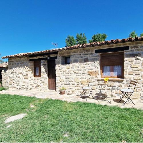 a stone house with a table and chairs outside at La Cabaña de Conquezuela in Conquezuela