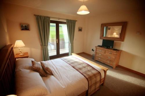 a bedroom with a bed and a window and a dresser at Plum Tree Lodge in Errol