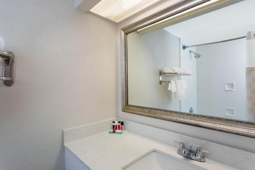 ein Badezimmer mit einem Waschbecken und einem großen Spiegel in der Unterkunft 88 Palms Hotel & Event Center in West Palm Beach