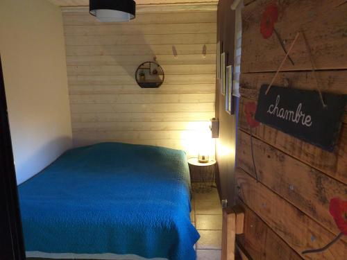 - une chambre avec un lit bleu et un mur en bois dans l'établissement Longère lotoise 5 chambres, à Sénaillac-Latronquière