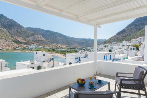 a balcony with chairs and a table and a view of the ocean at Sifnos House - Rooms and SPA in Kamarai