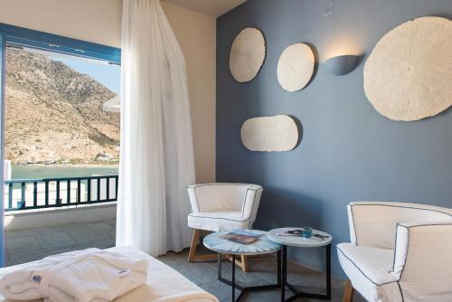 a room with two chairs and a bed and a window at Sifnos House - Rooms and SPA in Kamarai