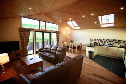 a living room with a couch and a table and a kitchen at Apple Tree Lodge in Errol