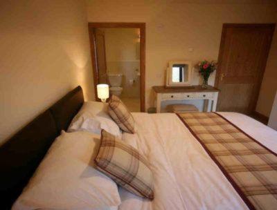 a bedroom with a large bed with two pillows at Apple Tree Lodge in Errol