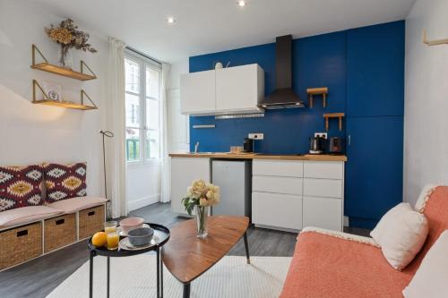 une cuisine aux murs bleus et un salon dans l'établissement Studio Bon'Air - Welkeys, à Biarritz