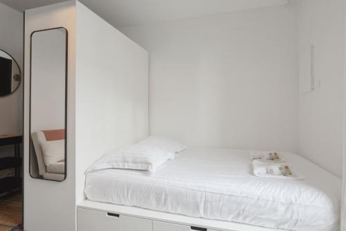 Cette chambre blanche comprend un lit et un miroir. dans l'établissement Studio Bon'Air - Welkeys, à Biarritz