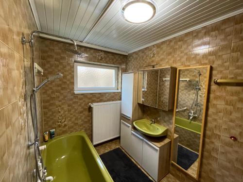 a bathroom with a green tub and a sink at Meli's Zirbenbett Ferienappartment in Bernstein