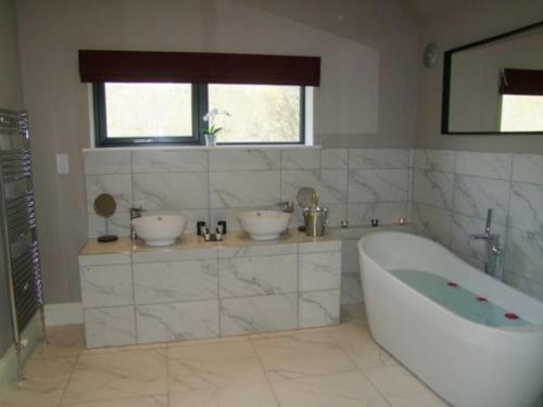 een badkamer met 2 wastafels en een bad bij Snowdrop Lodge in Errol