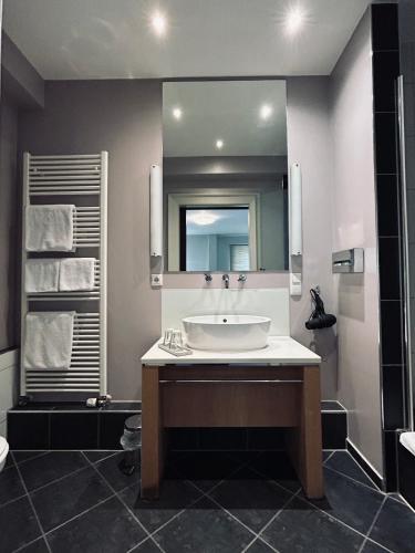 a bathroom with a sink and a large mirror at Hotel BRASSERIE in Erlangen
