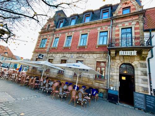 un groupe de tables avec parasols devant un bâtiment dans l'établissement Hotel BRASSERIE, à Erlangen