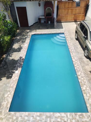 una piscina azul con un coche estacionado al lado en Residencia Isidora - Casa de Playa, en Punta Hermosa