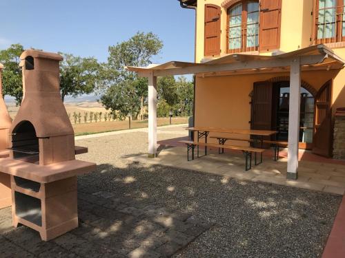 a building with a pizza oven and a picnic table at Borgo del Silenzio - Apartments with pool in Lajatico in Laiatico