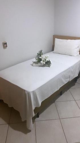 a bed with a white sheet and flowers on it at ELL PALACE HOTEL in Itaberaí