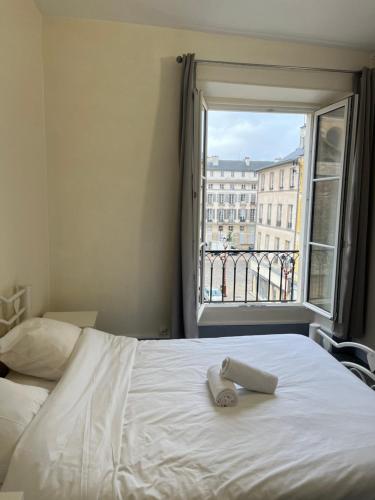 Una cama con una toalla en una habitación con ventana en L’ESPERANCE, en Versalles