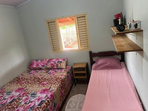 a small bedroom with two beds and a window at Rancho São Francisco in São Roque de Minas