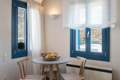 a table with two chairs and a bowl of fruit on it at Sifnos House - Rooms and SPA in Kamarai