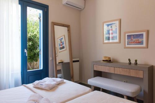 a bedroom with a bed and a desk and a window at Sifnos House - Rooms and SPA in Kamarai