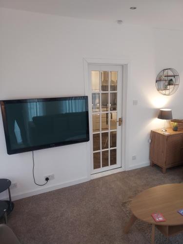 a living room with a large flat screen tv on the wall at The Old Forestry Cottage in Portree