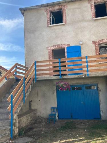 un bâtiment avec une porte bleue, des escaliers et une chaise dans l'établissement Maisonnette de charme, à Le Villard