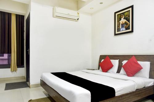 1 dormitorio con 1 cama grande con almohadas rojas en Super Collection O 81293 Hotel Aditya Palace, en Bhopal