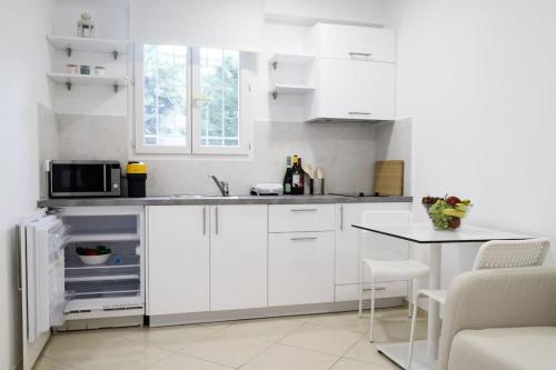 a white kitchen with white cabinets and a table at Cozy apartment near Airport in Koropi