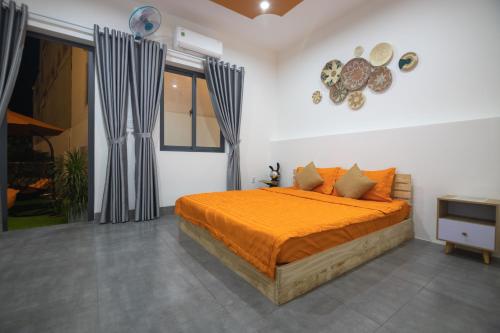 una camera da letto con un letto e un piumone arancione di PAL coffee & homestay a Vung Tau