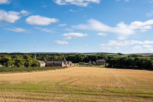 an open field with a farm in the distance at Ploughman's Bothy at Papple Steading in East Linton