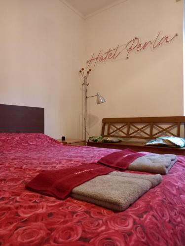 a bedroom with a bed with red sheets and a sign on the wall at La Perla di Vanchiglia (500 meters from the Mole) in Turin