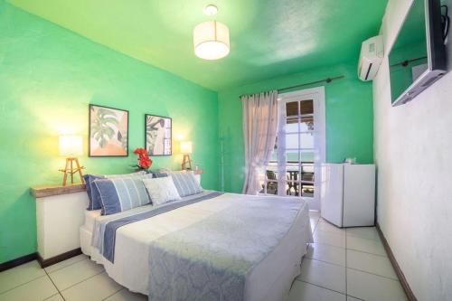a green bedroom with a bed and a refrigerator at Pousada dos Gravatás in Búzios