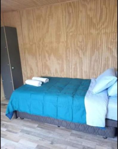 Una cama azul con dos toallas encima. en Cabañas MR, en Llanquihue