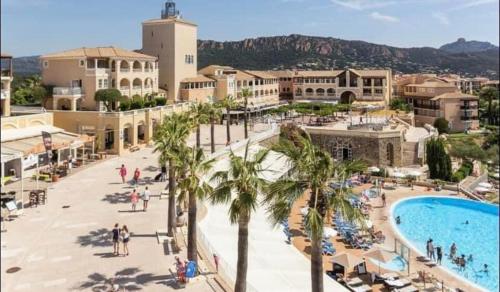 - une vue sur un complexe avec une piscine et des palmiers dans l'établissement CAP Estérel pierre et vacances Type 3 , 2 chambres Rez de jardin clôturé ,vue Mer ,Inclus climatisation place de stationnement , accès aux Piscines ,animations, à Saint-Raphaël