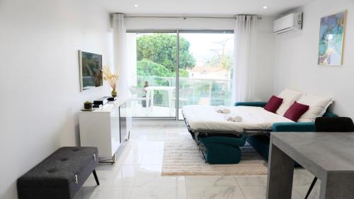 ein Wohnzimmer mit einem Bett und einem Tisch in der Unterkunft Magnifique studio, piscine, Parking By Palmazur in Cannes