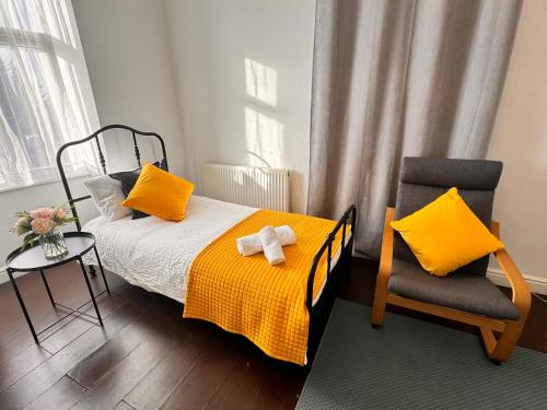 a bedroom with a bed with yellow pillows and a chair at Acacia Flat 189 in Wembley in London