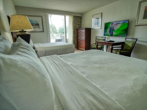 a bedroom with a large white bed and a desk at Treasure Island Hotel and Marina in St Pete Beach