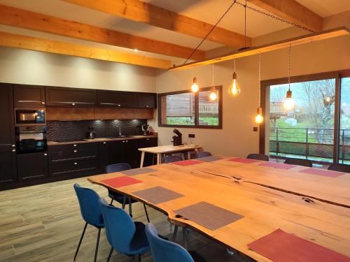une cuisine avec une grande table en bois et des chaises bleues dans l'établissement Chalet Lignum, Exceptionnel - Sauna & SPA - vue sur les montagnes, 8 minutes des pistes., à La Bresse