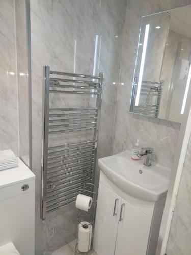 a white bathroom with a sink and a mirror at 4B Wentworth Street Apartment in Portree