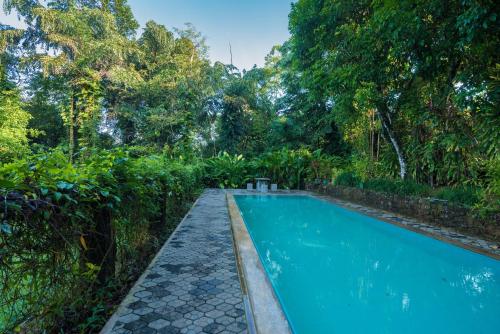 a swimming pool in a garden with trees at Udapola Bungalow by Lalan Leisure in Deraniyagala