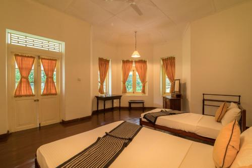 um quarto com 2 camas e um quarto com janelas em Udapola Bungalow em Deraniyagala