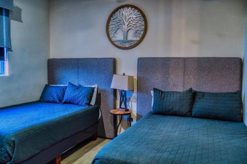 a bedroom with two beds and a tree picture on the wall at Casa Azul F2 in Puerto Peñasco