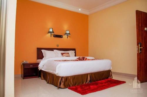 a bedroom with a large bed with an orange wall at EAGLES NEST INT. HOTEL in Tarkwa